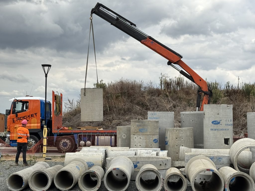 crane unloading donated concrete pipes for infrastructure rebuild project